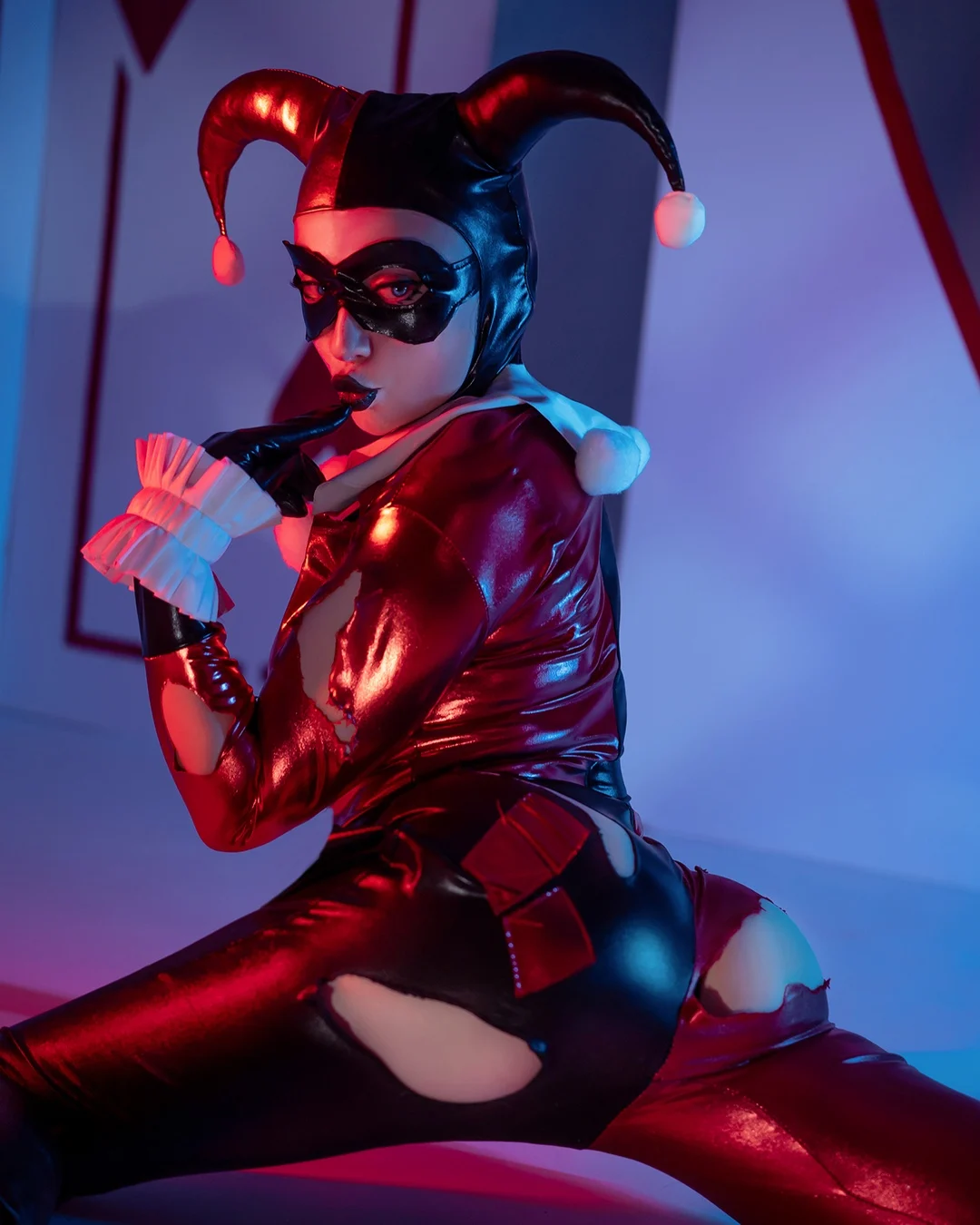 Ira in a red and black harlequin costume holding playing cards